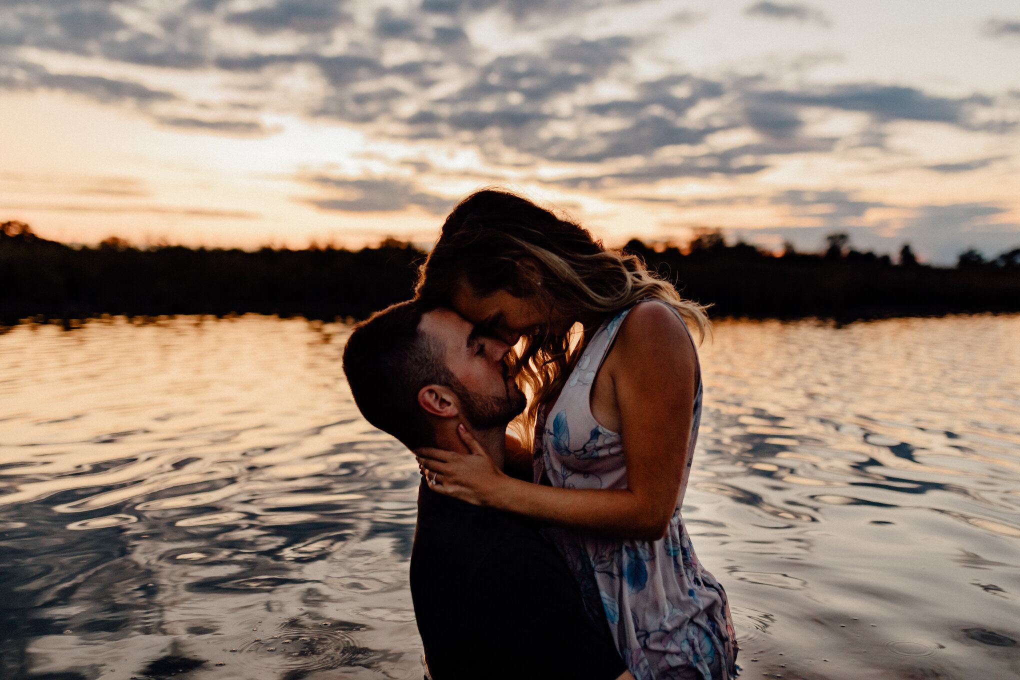  engaged couple in ottawa lake getting close at sunset with foreheads together 