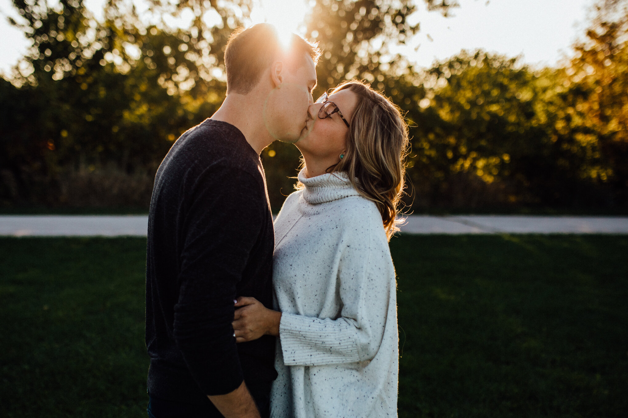  engaged-couple-kissing-in-field-with-sunshine-in-milwaukee-engagement-session.jpg 