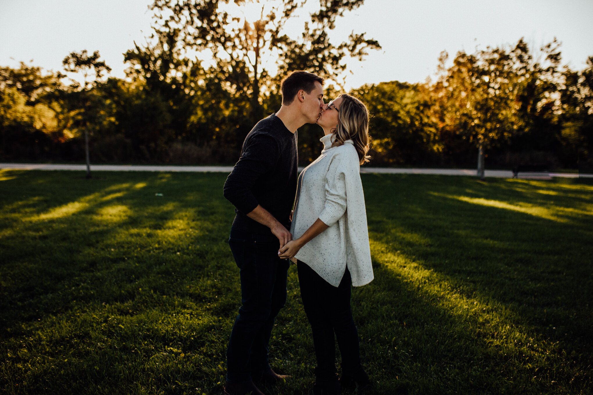  engaged couple kissing in field with sunshine in milwaukee engagement session 