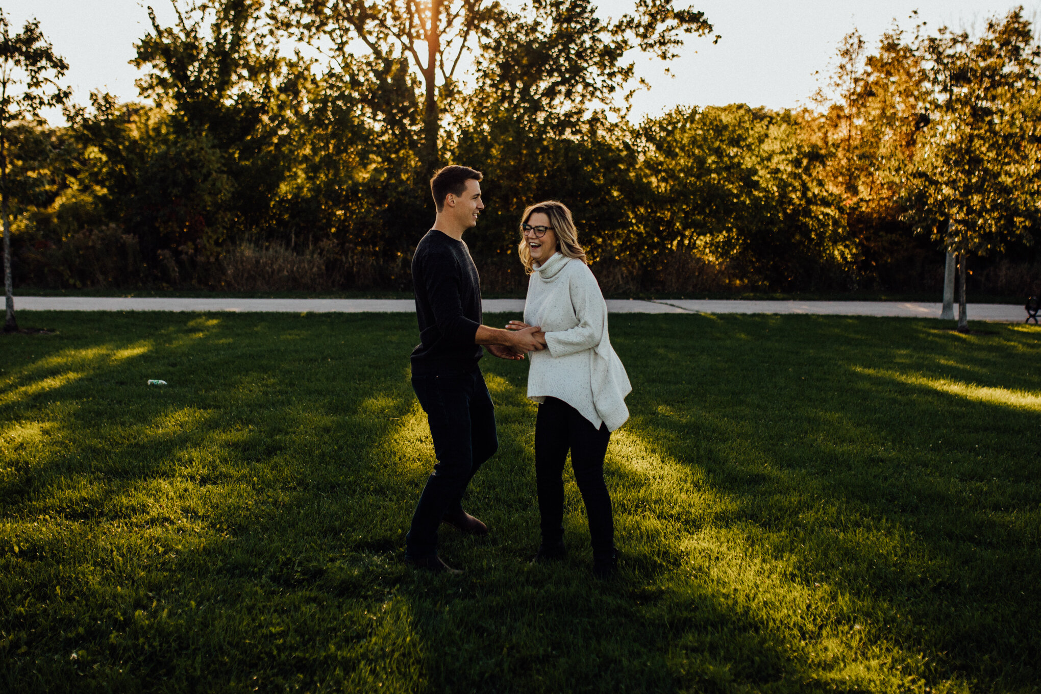  engaged couple spinning in field with sunshine in milwaukee engagement session 