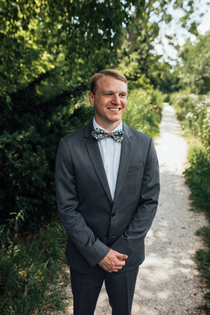 Groom standing in grey suit with turquoise floral tie