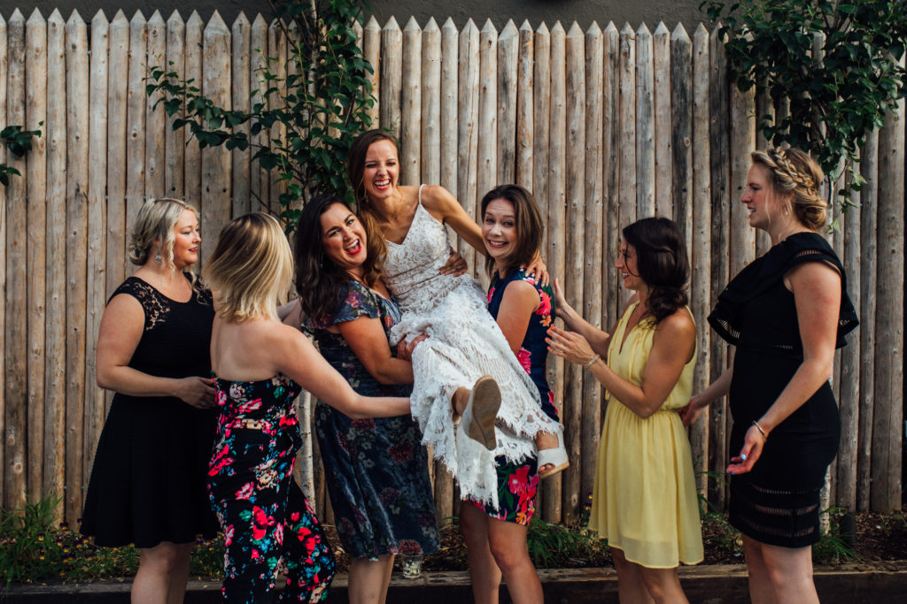 Bride's college friends pick her up in the air and laugh