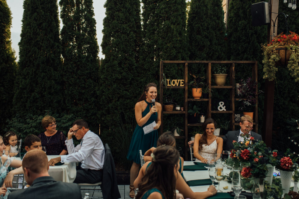 Bridesmaid speaks during dinner on patio at Birch while bride and groom laugh