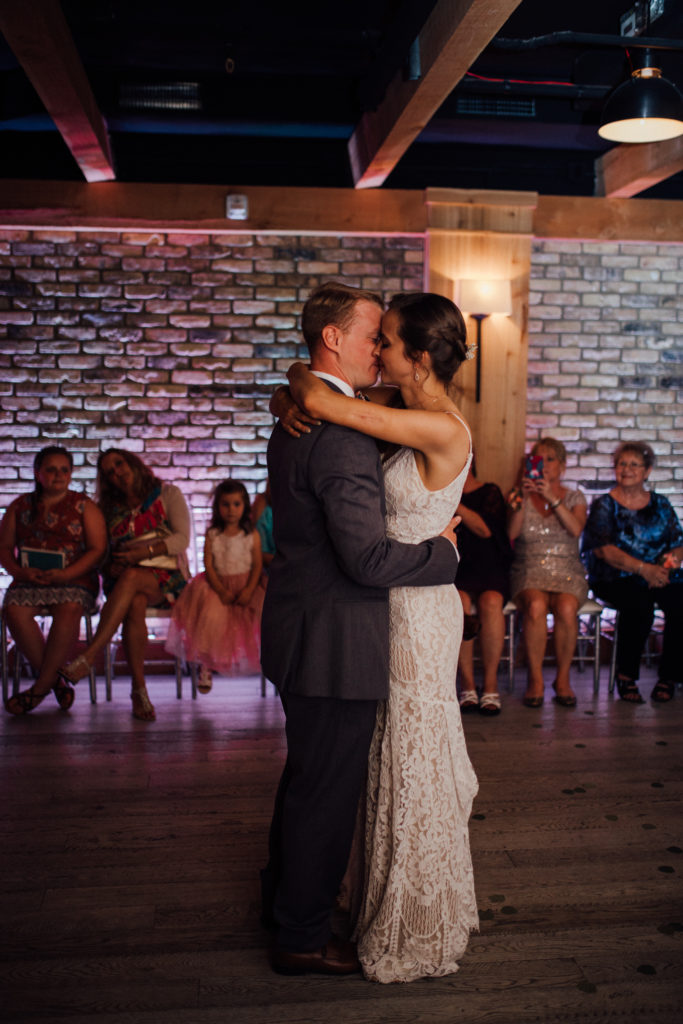 Bride and groom holding each other close and kiss during first dance at Birch