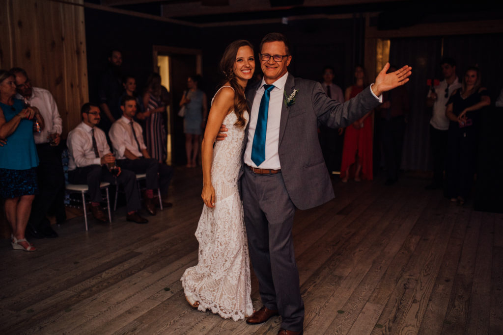 Father shows bride to camera during first dance