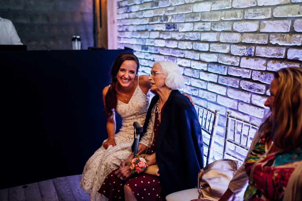 Bride chats with grandma on chairs near dance floor