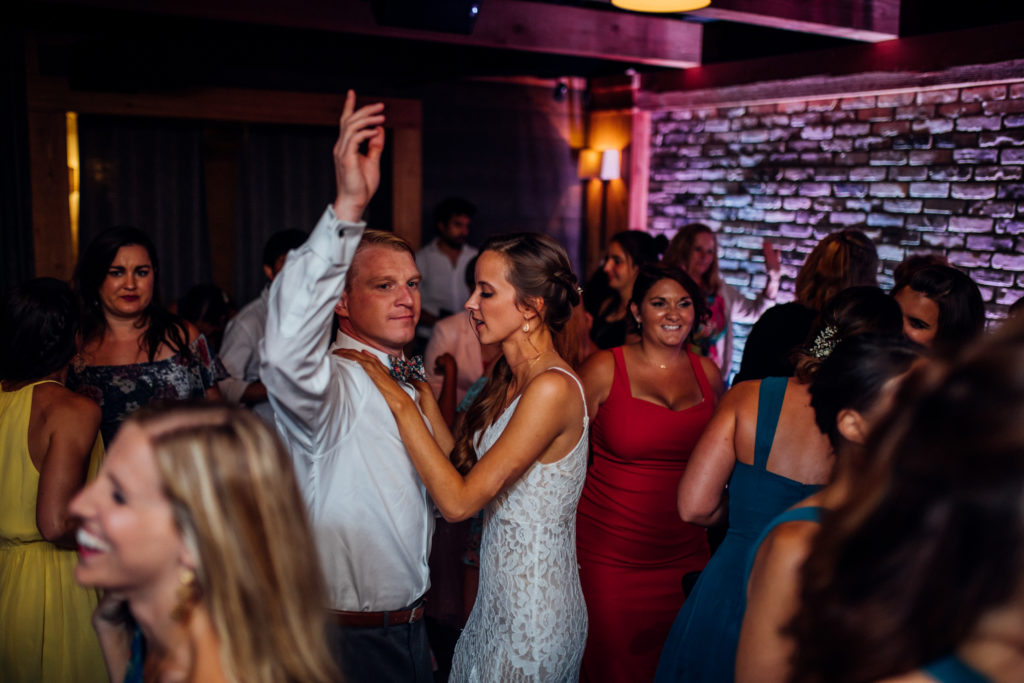 bride and groom dance with grooms hand lifted in the air