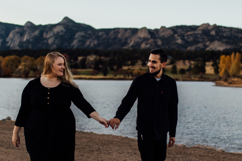 couple holding hands in front of estes lake