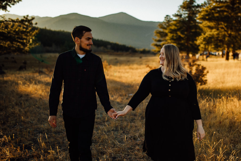couple looking at each other in rocky mountain national park at sunset with golden grass