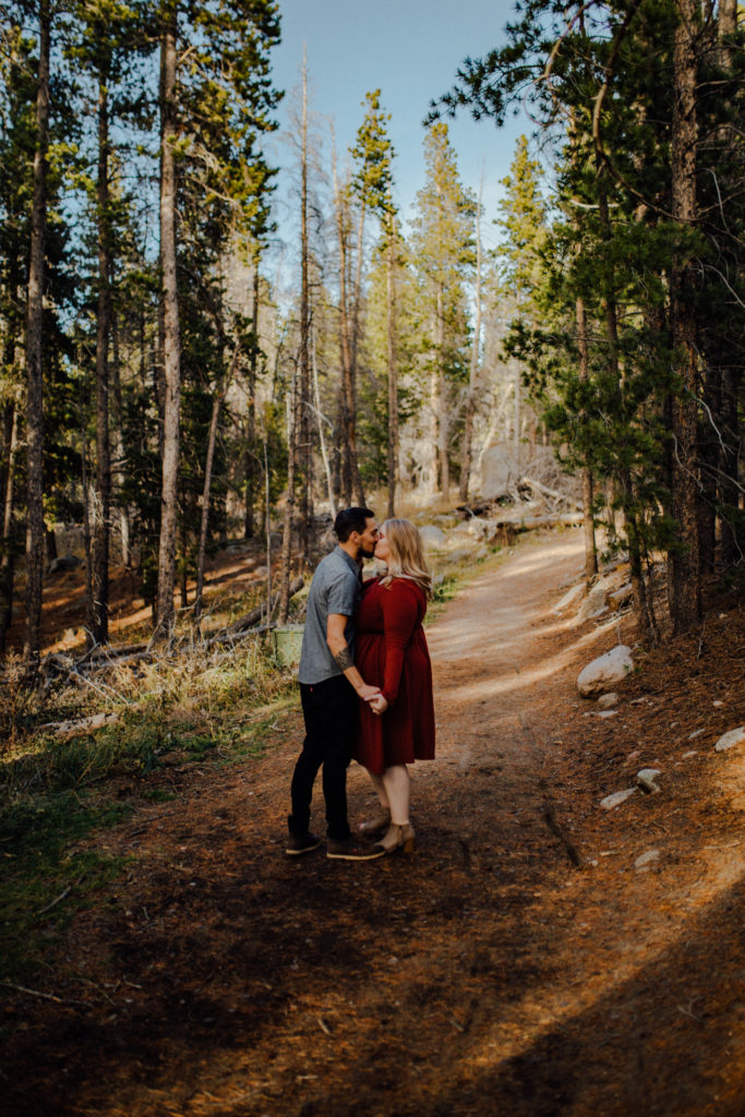 man and woman kiss in Rocky Mountain Park for engagement session