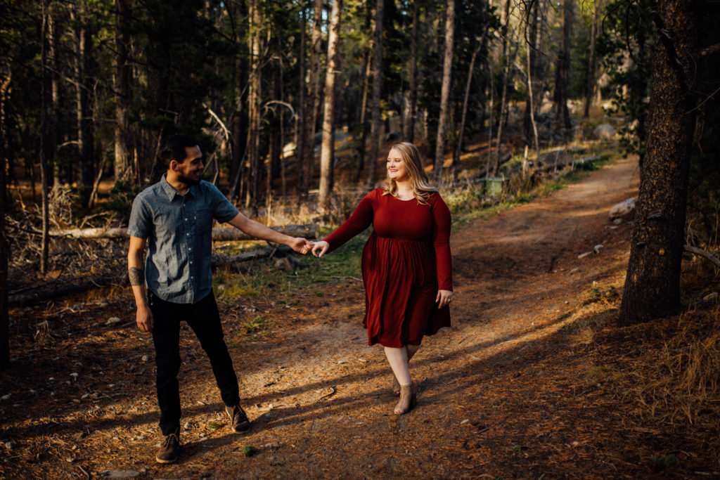 Man leads woman into woods with red dress