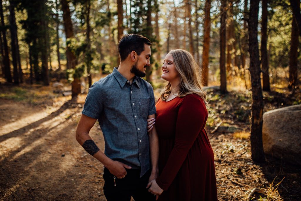 man and woman look at each other at sunset during Rocky Mountain Park engagement session