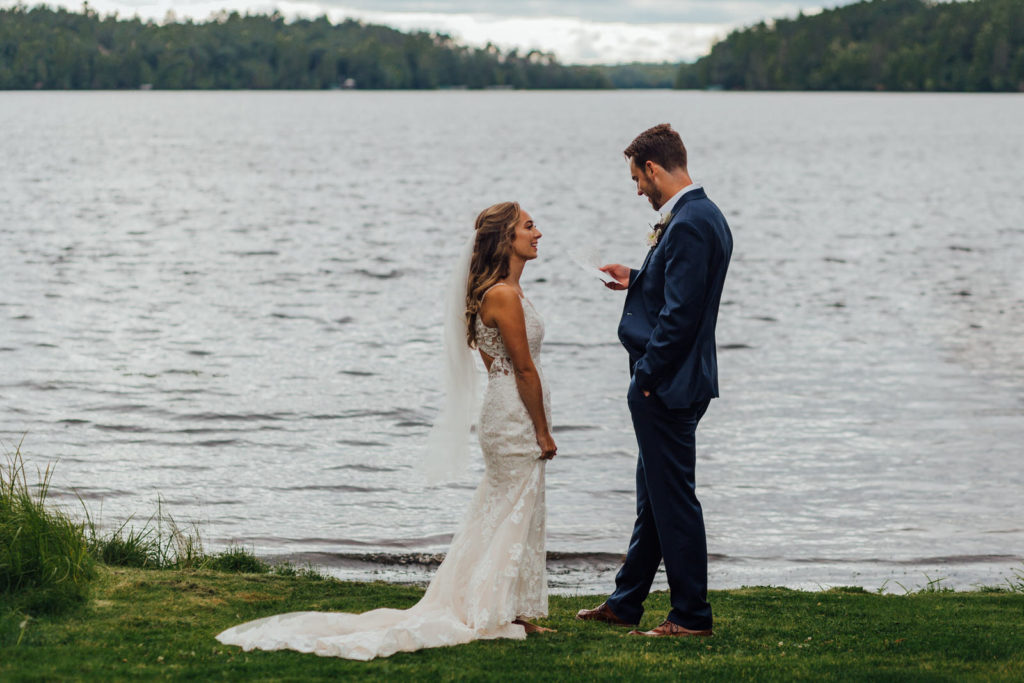 groom reads letter to groom during first look along scattering rice lake shore